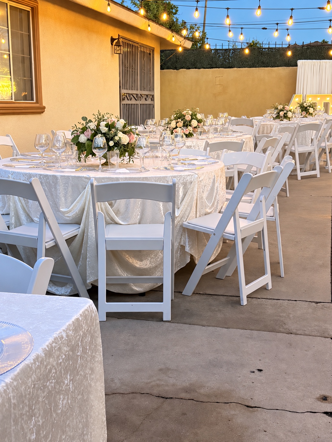 Ivory banquet tables and white chairs under string lights