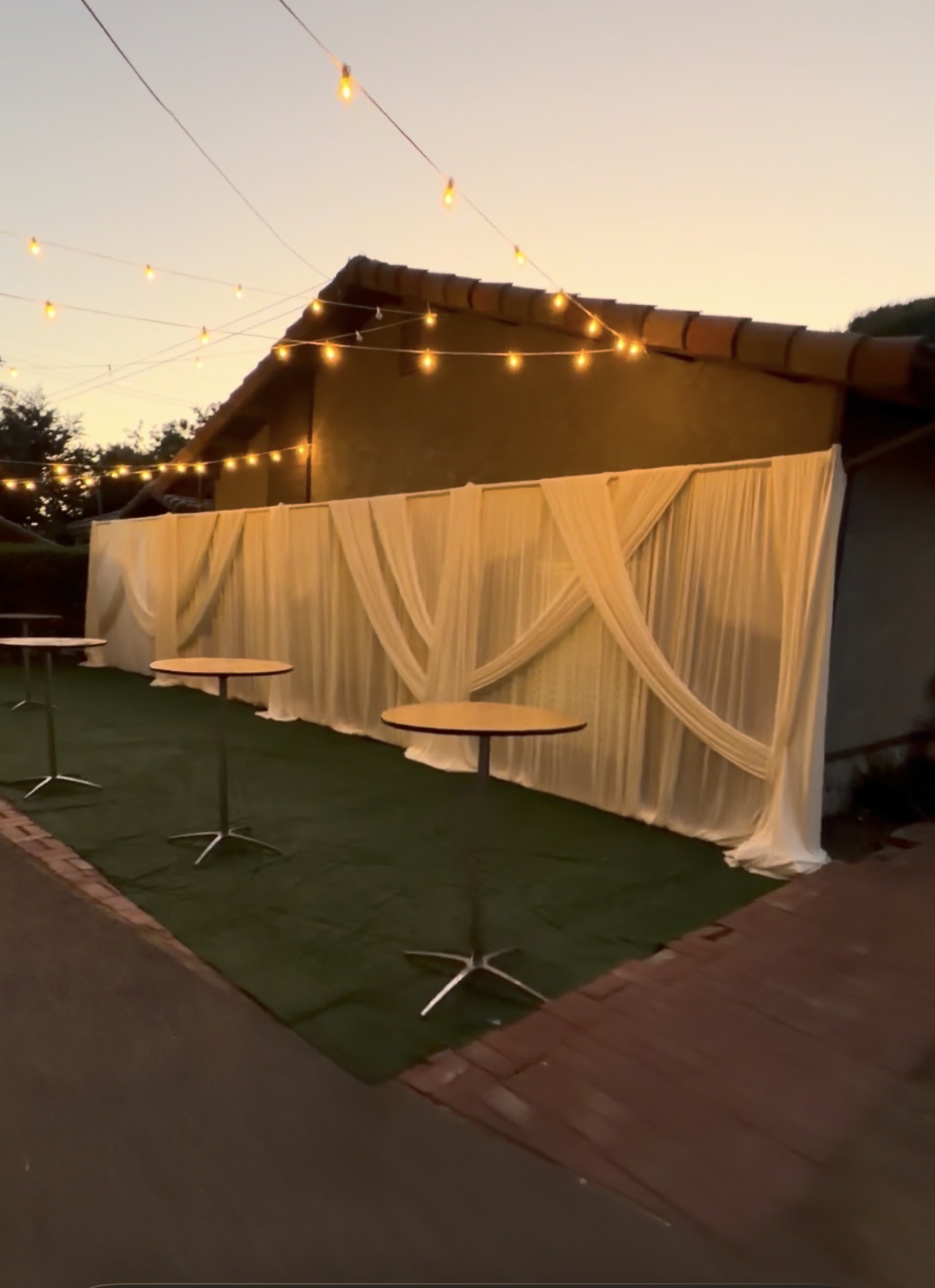 Ivory draping with warm string lights and cocktail tables