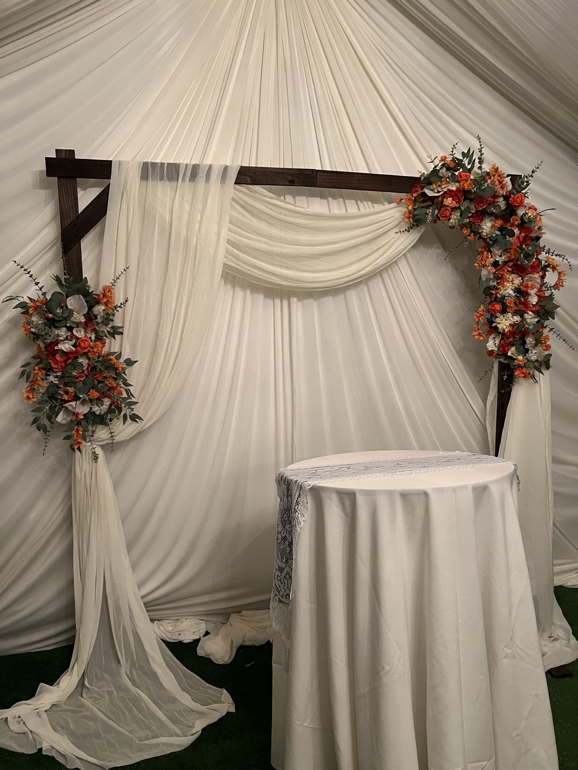 Ivory backdrop with orange floral arrangements