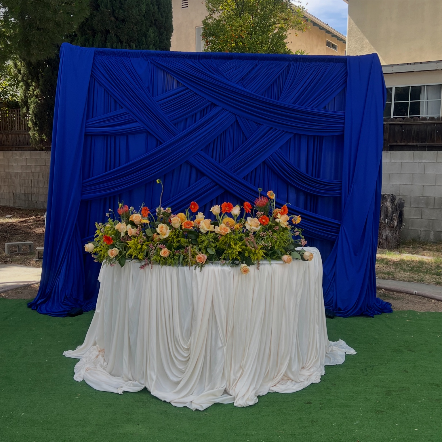 Royal blue draped backdrop with floral arrangement